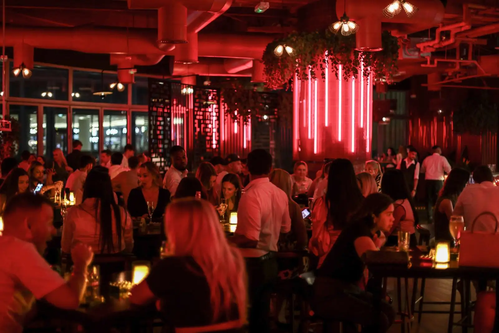 A full dining room under Cargo's red neon tubes