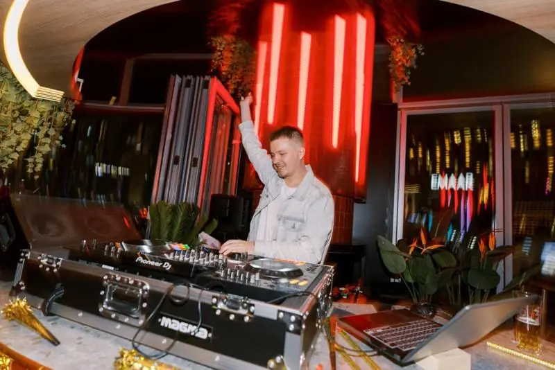 The DJ at the booth in daylight under the neon